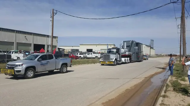Bonafide pilot truck and a heavy machinery load in an industrial yard