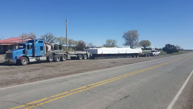 Long white load on a lowboy along a highway