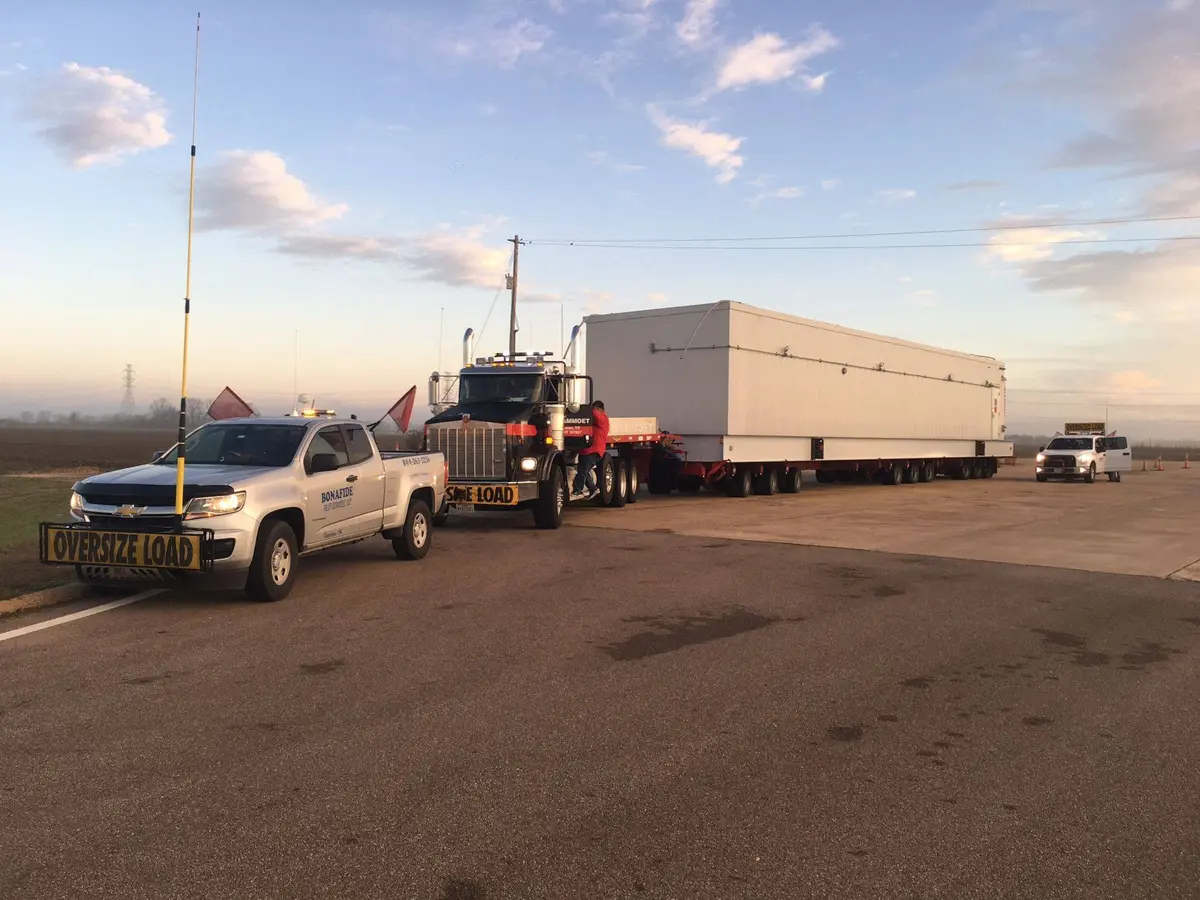 Bonafide pilot truck escorting a modular building at sunset
