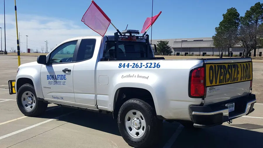 Bonafide pilot truck with flags and an oversize load sign