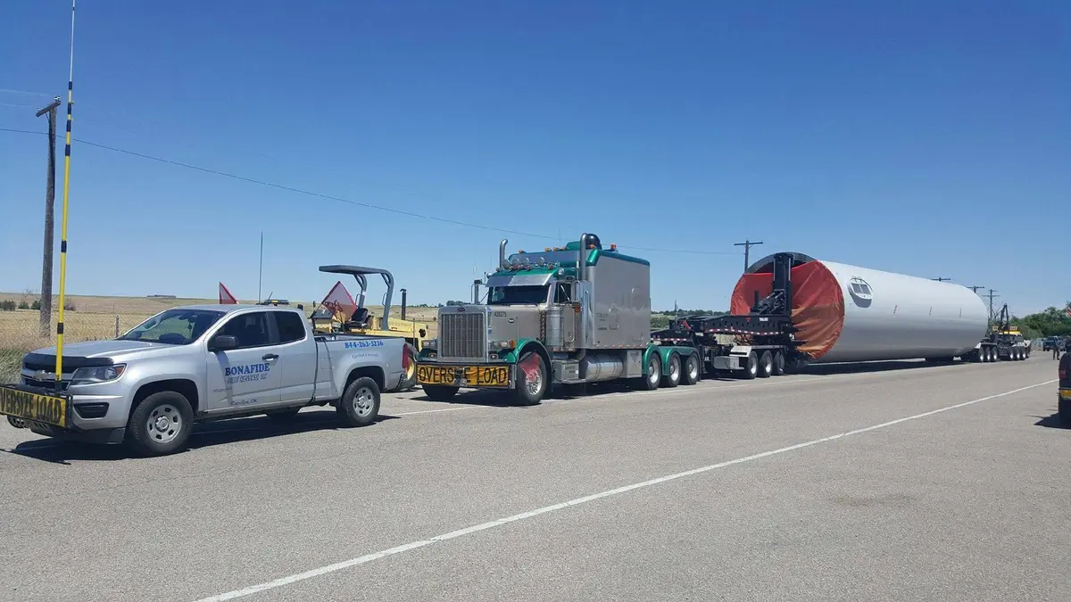 Bonafide pilot truck staged with a wind tower section on a heavy haul trailer